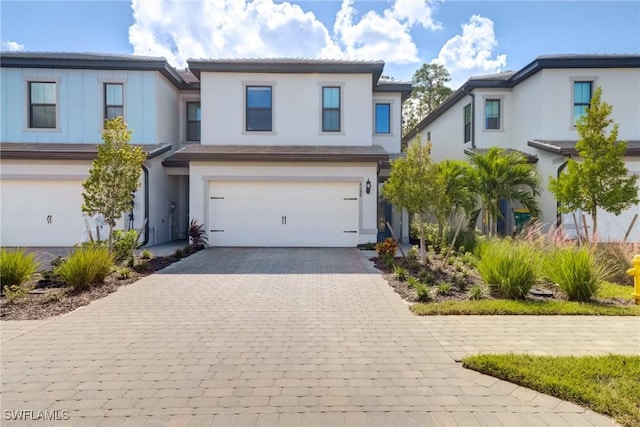 view of front of house with stucco siding, decorative driveway, and a garage