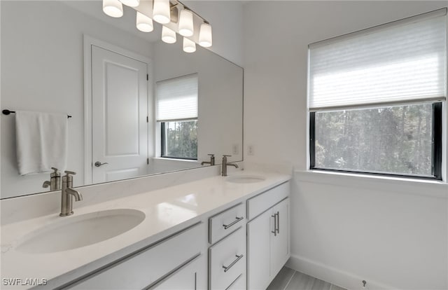 full bathroom with double vanity, baseboards, and a sink