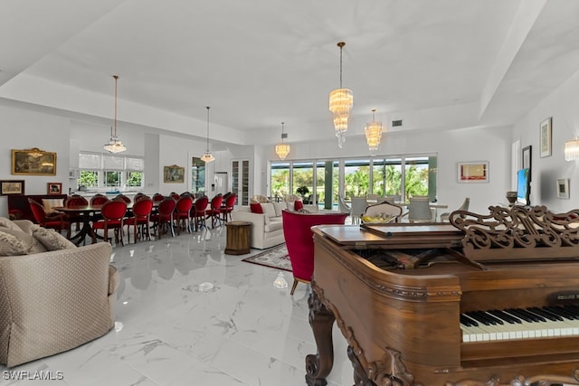 living room featuring a tray ceiling, an inviting chandelier, and plenty of natural light