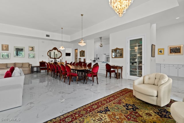 dining space featuring a raised ceiling and an inviting chandelier