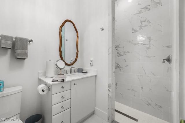 bathroom with vanity, a tile shower, and toilet