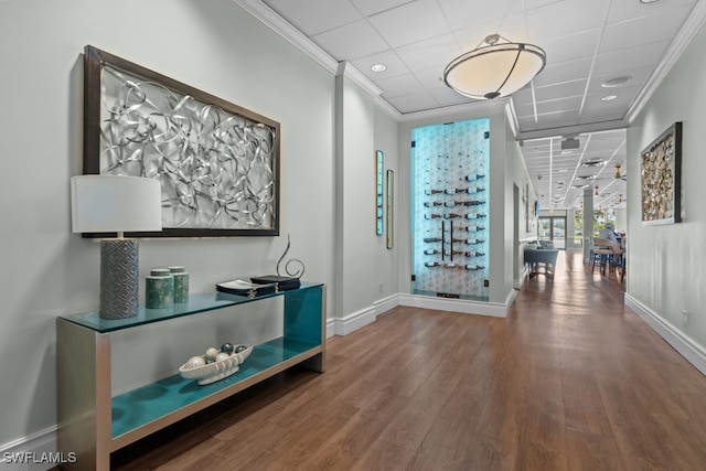 corridor featuring crown molding, wood-type flooring, and a paneled ceiling