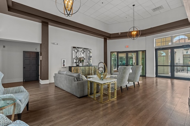 living room featuring a chandelier, french doors, dark hardwood / wood-style floors, and a towering ceiling