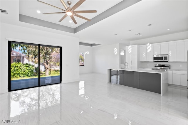 kitchen featuring white cabinetry, ceiling fan, a large island, hanging light fixtures, and stainless steel appliances