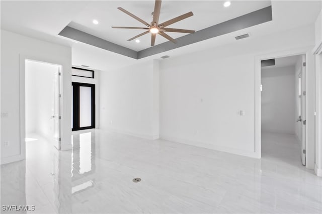 unfurnished room featuring a raised ceiling and ceiling fan