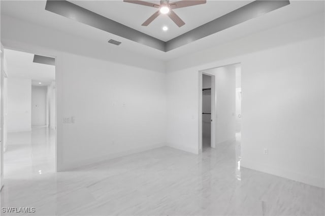 empty room featuring a tray ceiling and ceiling fan