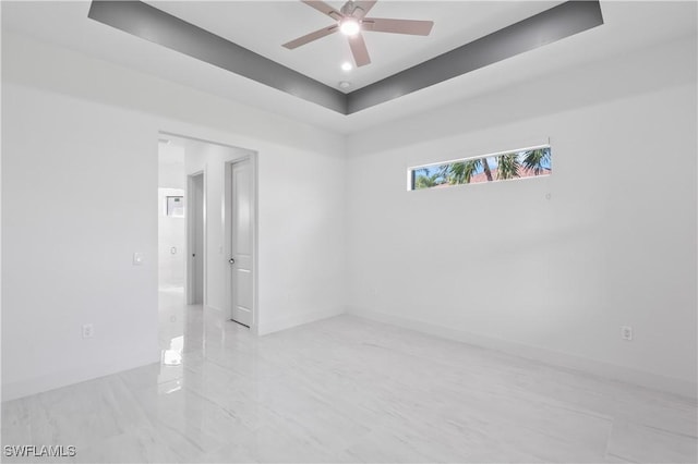 spare room featuring ceiling fan and a raised ceiling