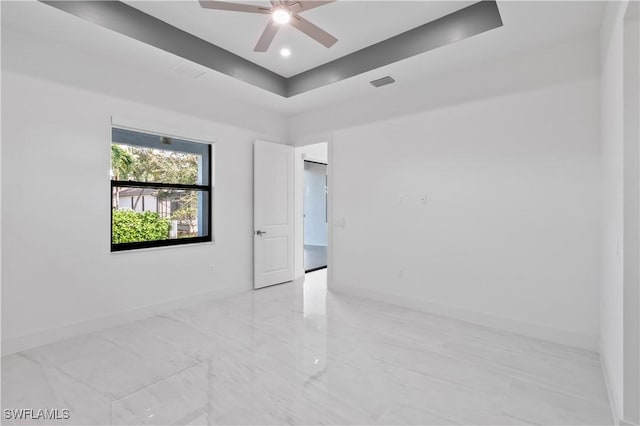 spare room featuring a tray ceiling and ceiling fan