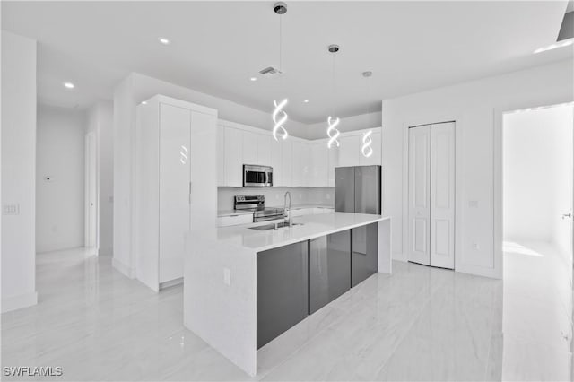 kitchen with white cabinets, stainless steel appliances, hanging light fixtures, and a kitchen island with sink