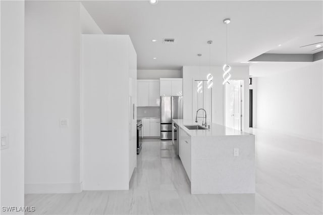 kitchen featuring sink, pendant lighting, a kitchen island with sink, white cabinets, and appliances with stainless steel finishes