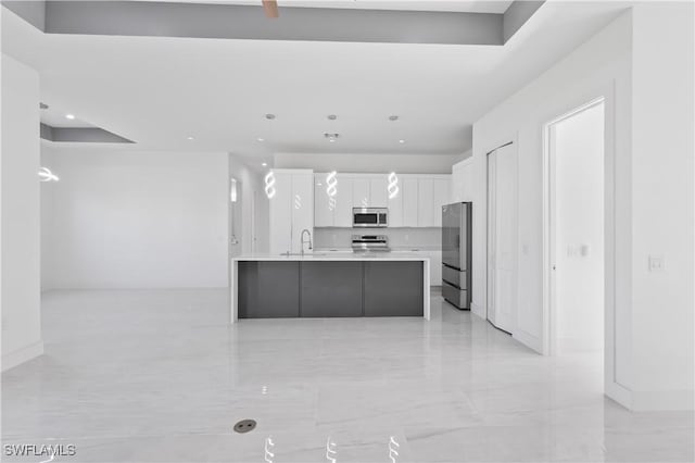 kitchen with a spacious island, sink, appliances with stainless steel finishes, decorative light fixtures, and white cabinetry