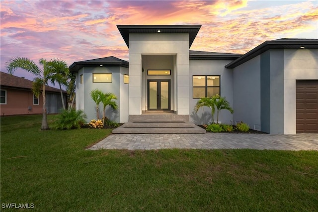 exterior entry at dusk with a yard and a garage