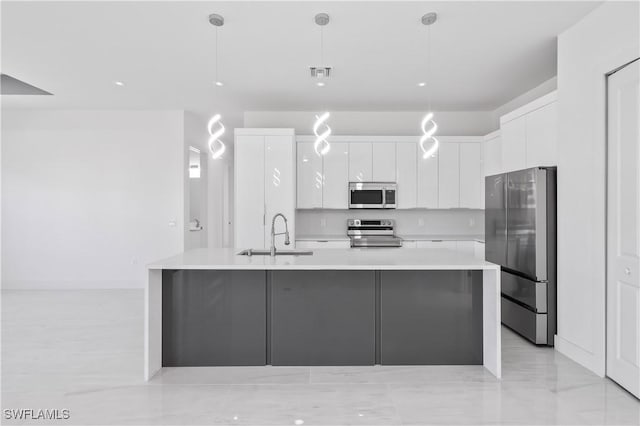 kitchen with white cabinets, appliances with stainless steel finishes, decorative light fixtures, and sink