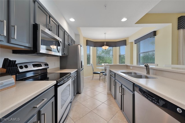 kitchen with pendant lighting, stainless steel appliances, sink, and a wealth of natural light