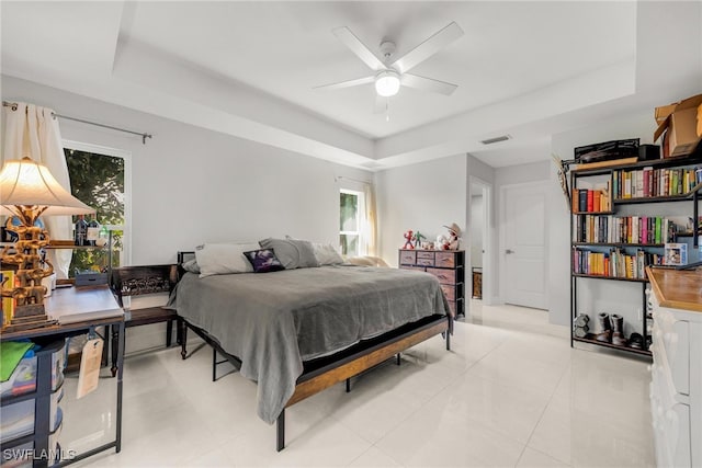 tiled bedroom featuring a tray ceiling and ceiling fan