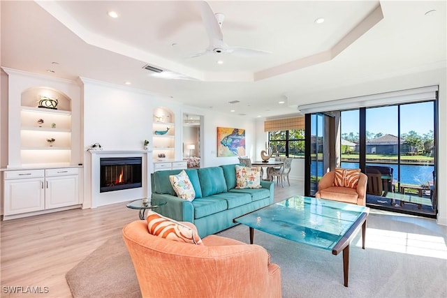 living room with ceiling fan, a healthy amount of sunlight, a raised ceiling, and built in features