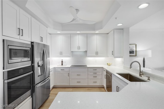 kitchen with light wood-type flooring, light stone counters, stainless steel appliances, sink, and white cabinetry