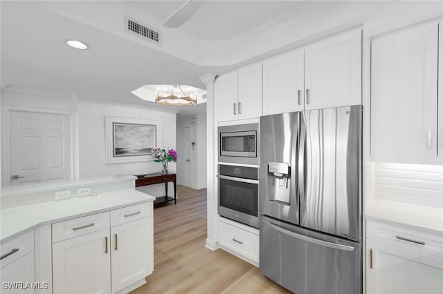 kitchen with light hardwood / wood-style flooring, stainless steel appliances, a chandelier, and white cabinetry