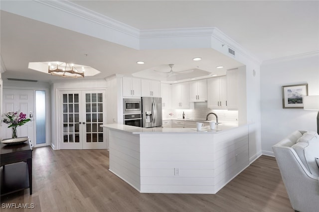 kitchen with light countertops, backsplash, appliances with stainless steel finishes, and crown molding