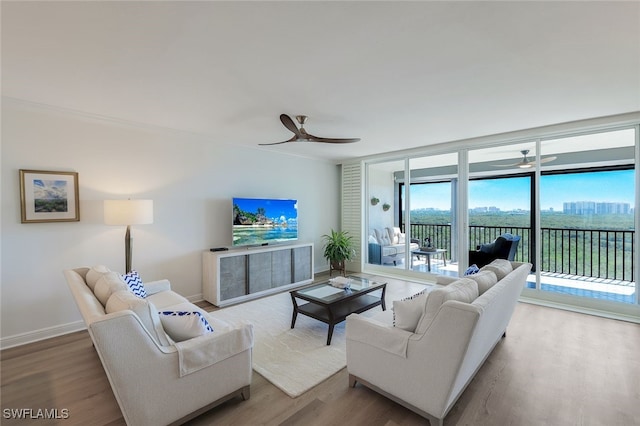 living area with baseboards, wood finished floors, and ceiling fan
