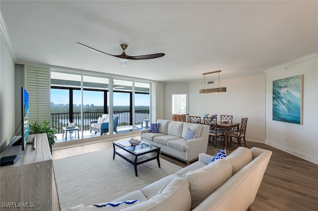 living room with a water view, ceiling fan, hardwood / wood-style flooring, a wall of windows, and crown molding