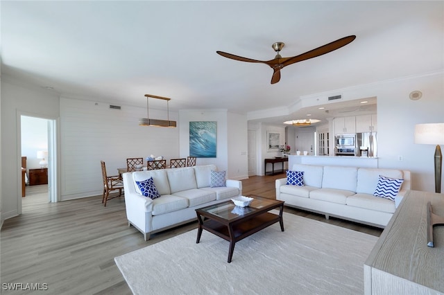 living room featuring crown molding, light hardwood / wood-style flooring, and ceiling fan