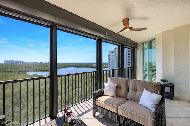 sunroom / solarium featuring a ceiling fan and a water view