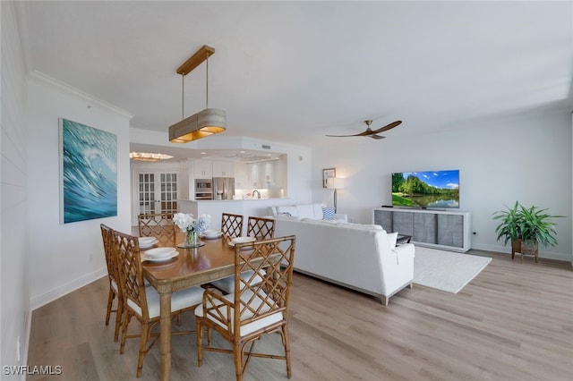 dining space featuring a ceiling fan, baseboards, ornamental molding, and light wood-style flooring