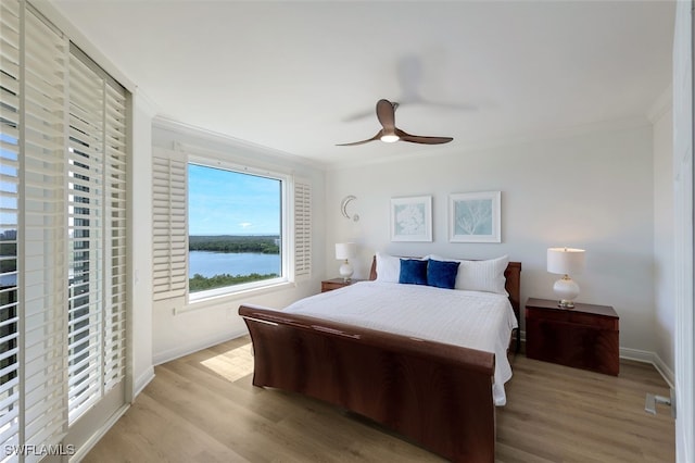 bedroom featuring ornamental molding, a water view, ceiling fan, and light hardwood / wood-style flooring