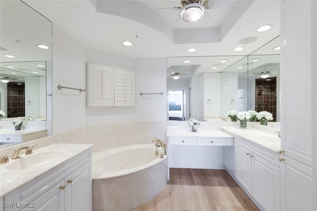 bathroom with a tub with jets, wood finished floors, a sink, ceiling fan, and recessed lighting