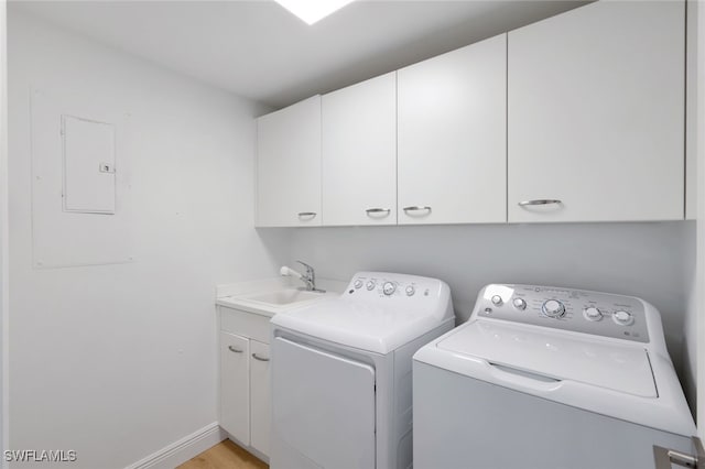 clothes washing area with electric panel, sink, light hardwood / wood-style flooring, cabinets, and washing machine and dryer