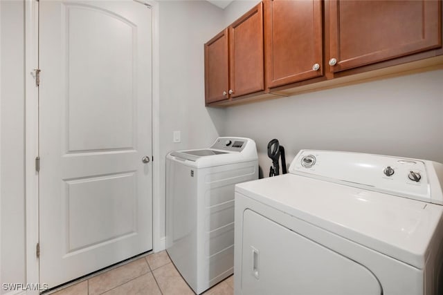 washroom with cabinets, washing machine and dryer, and light tile patterned flooring