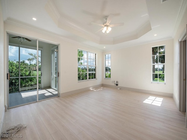 empty room with ceiling fan, crown molding, light hardwood / wood-style floors, and a raised ceiling