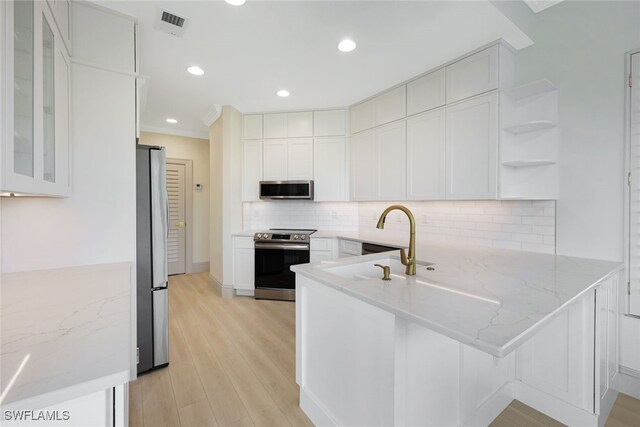 26831 Wyndhurst Ct Unit 101, Bonita Springs, FL 34134 - kitchen with white cabinets, a peninsula, light stone counters, and stainless steel appliances