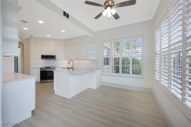 kitchen with kitchen peninsula, ceiling fan, stainless steel appliances, backsplash, and white cabinets