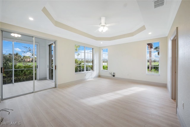 spare room with ceiling fan, ornamental molding, a raised ceiling, and light hardwood / wood-style flooring