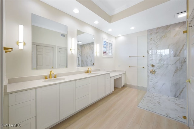 bathroom featuring ornamental molding, a tile shower, hardwood / wood-style flooring, and vanity