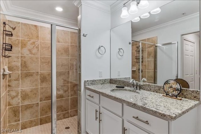 bathroom with vanity, a shower with shower door, and ornamental molding