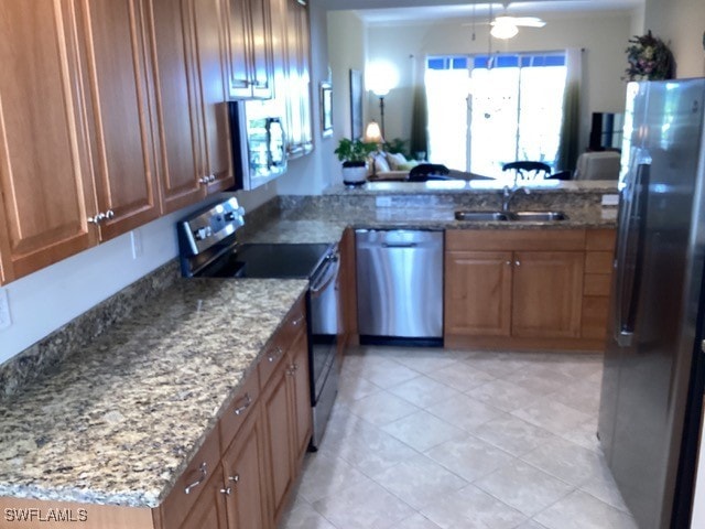 kitchen with stainless steel appliances, stone counters, sink, and kitchen peninsula