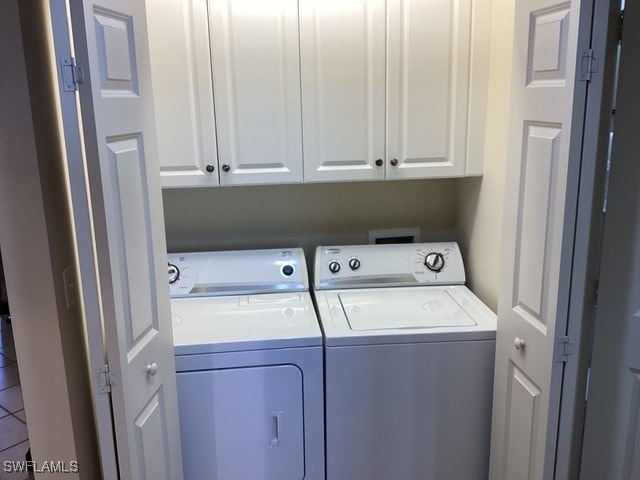 clothes washing area with cabinets and washer and dryer