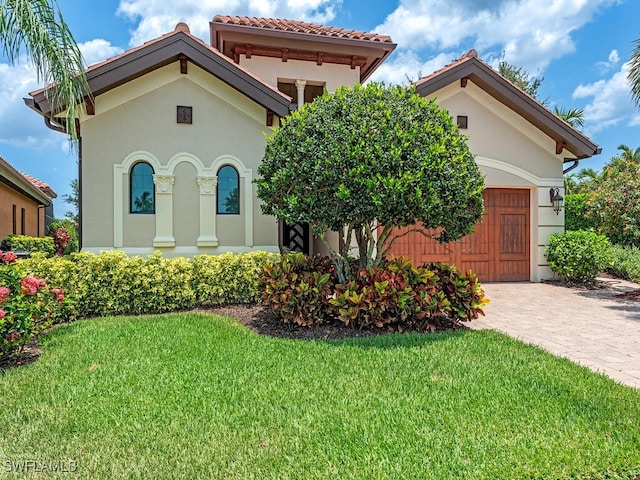 mediterranean / spanish-style house featuring a garage and a front lawn