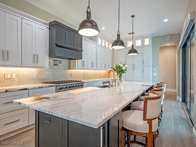 kitchen with premium range hood, a large island, pendant lighting, and sink