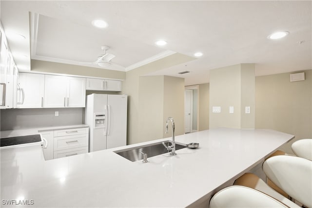 kitchen with white appliances, crown molding, a breakfast bar, sink, and white cabinetry