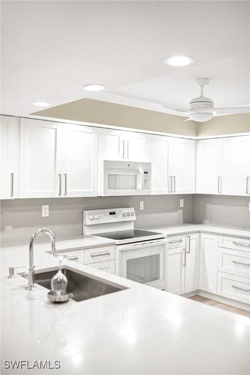 kitchen featuring a sink, white cabinets, and white appliances