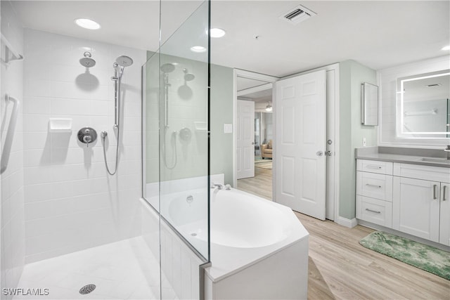 bathroom featuring plus walk in shower, hardwood / wood-style flooring, and vanity