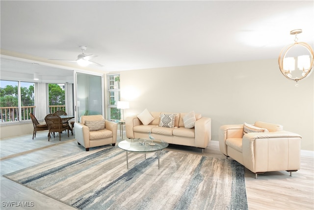 living room featuring ceiling fan with notable chandelier and light hardwood / wood-style floors