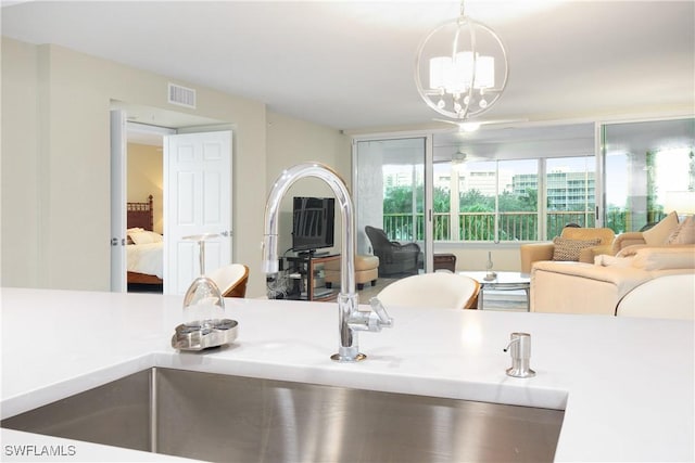 kitchen featuring visible vents, open floor plan, a chandelier, a sink, and hanging light fixtures