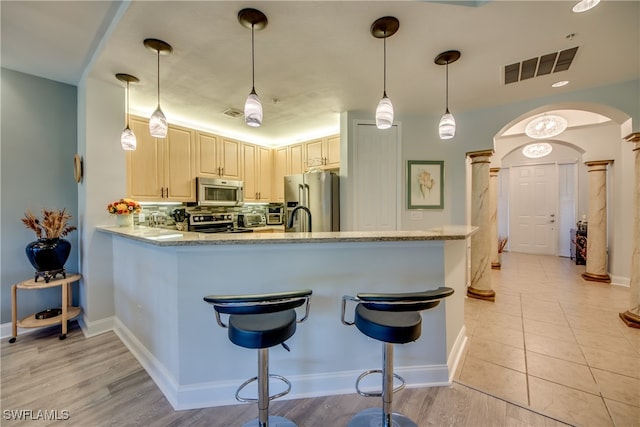 kitchen with pendant lighting, kitchen peninsula, appliances with stainless steel finishes, and light wood-type flooring