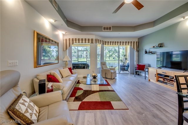 living room with ceiling fan, hardwood / wood-style flooring, and a tray ceiling