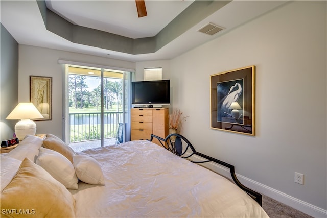 carpeted bedroom featuring access to exterior, ceiling fan, and a raised ceiling